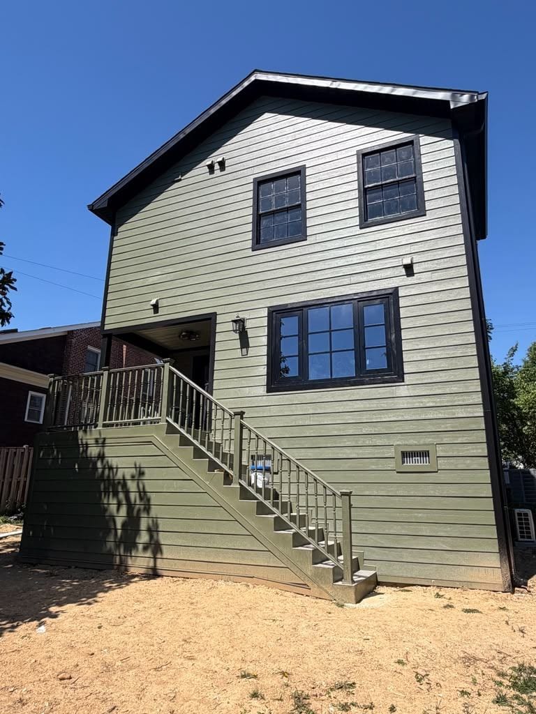 Two-story rear addition with green lap siding, black-trim windows and a new exterior stair