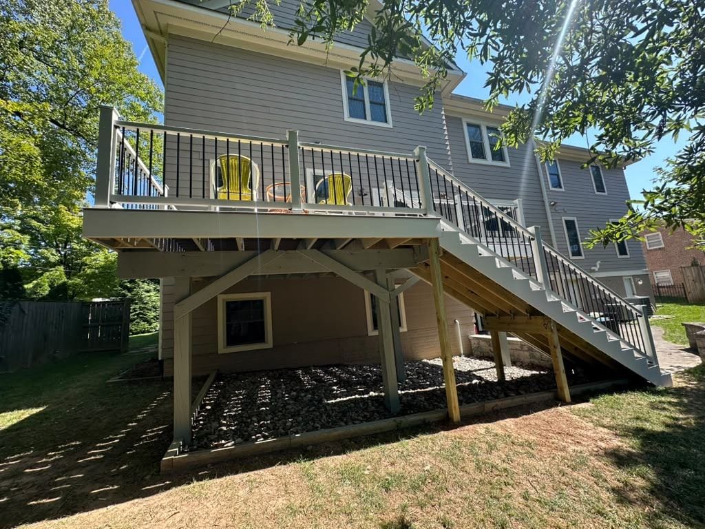 Composite deck with white rails and a stair down to the yard on the back of a two-story home