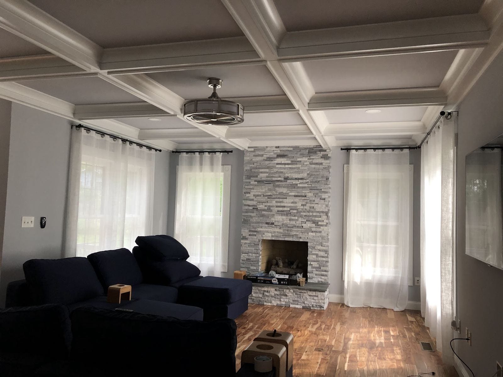 Family room addition in Springfield with a coffered ceiling, stacked-stone fireplace and hardwood floor