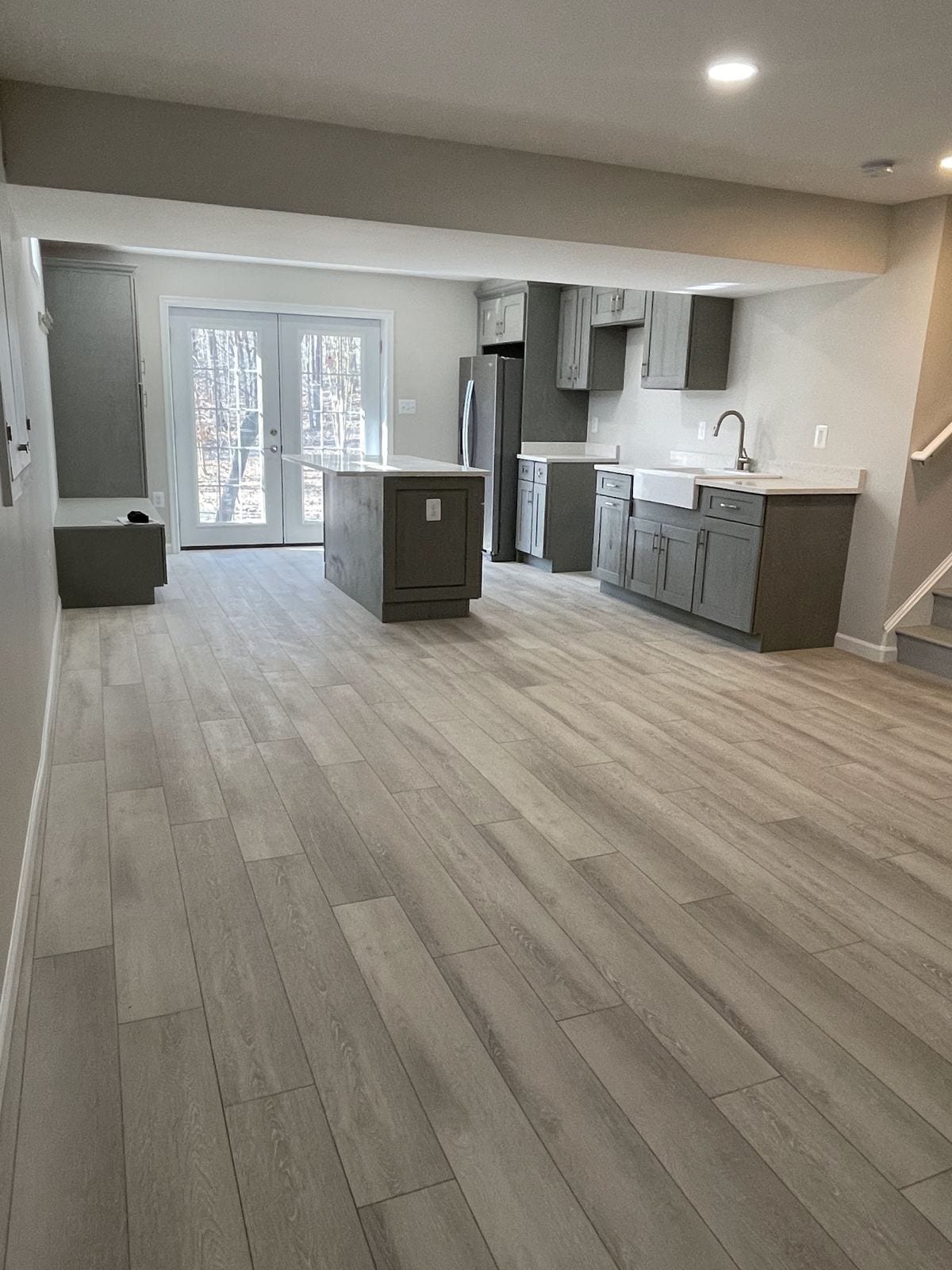 Open basement with a kitchenette, island and French doors to the yard