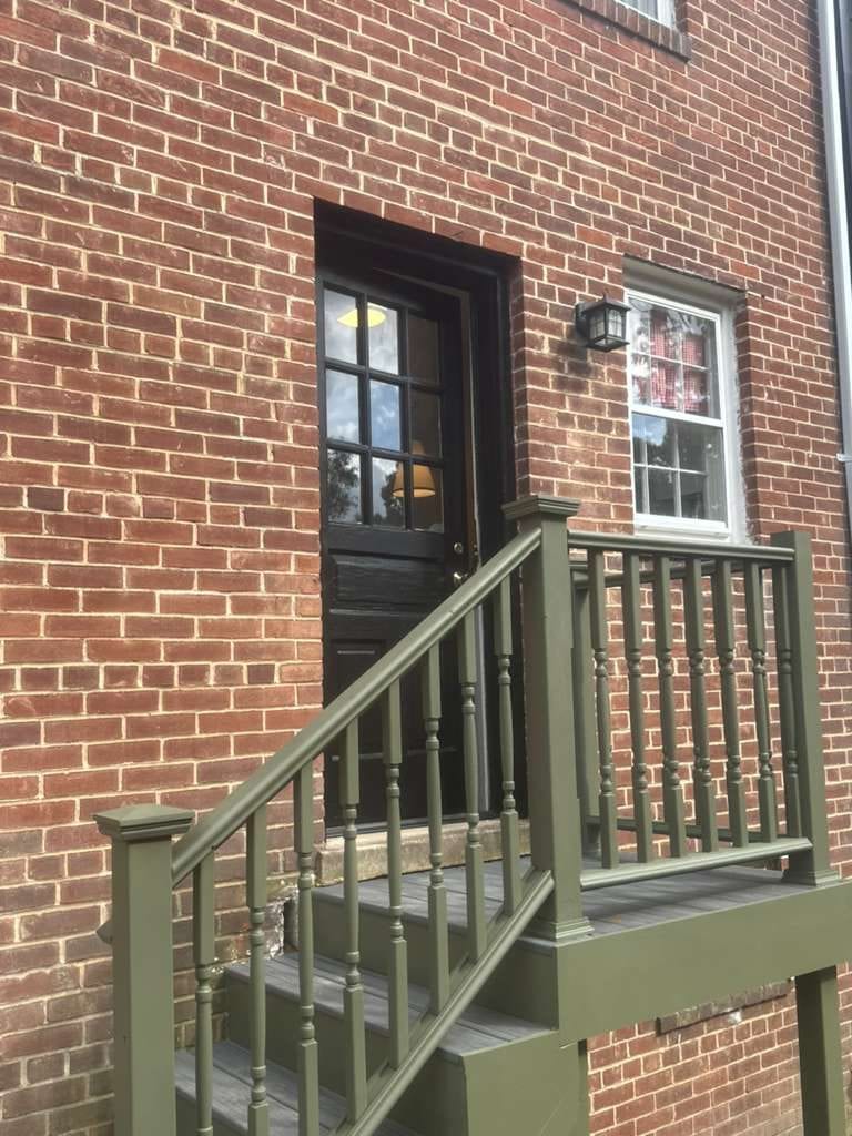 New painted entry stair and railing at a side door of a brick home