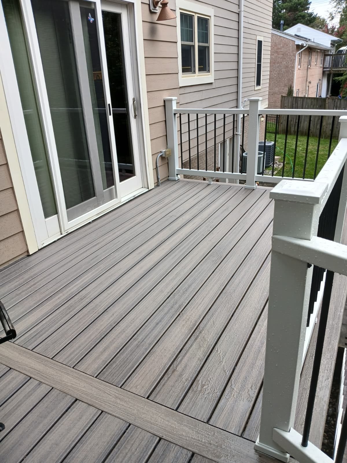 Composite deck boards and white railings outside a sliding glass door