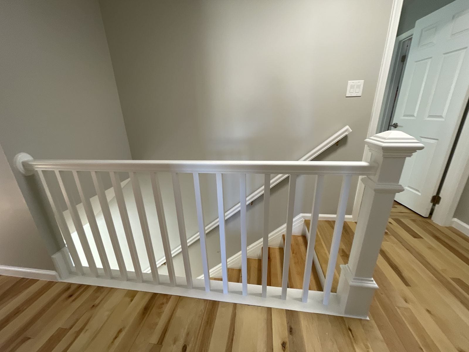 New white stair railing and balusters over hardwood flooring