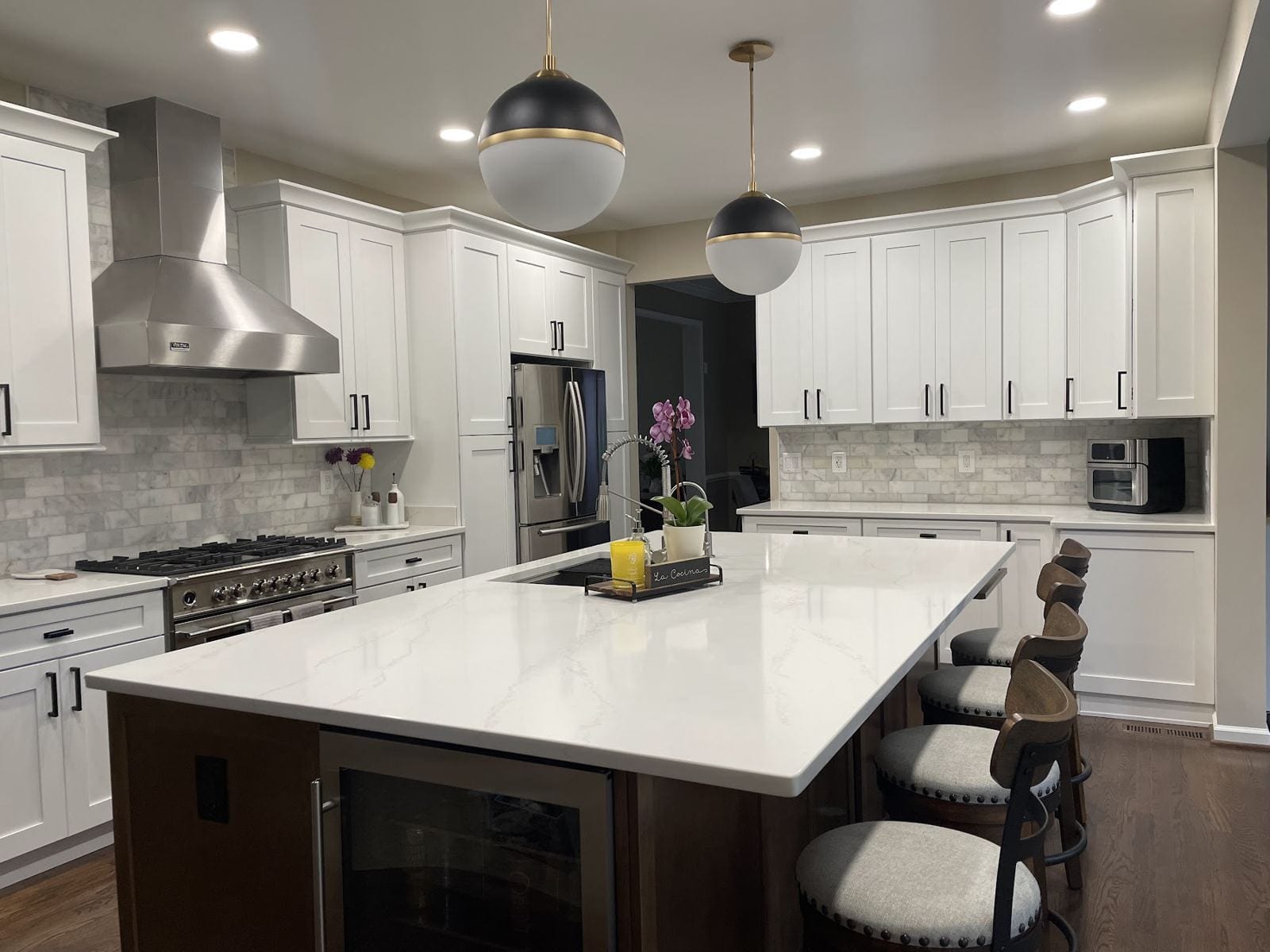 Kitchen remodel in Vienna with a large quartz island, stainless range hood and marble backsplash