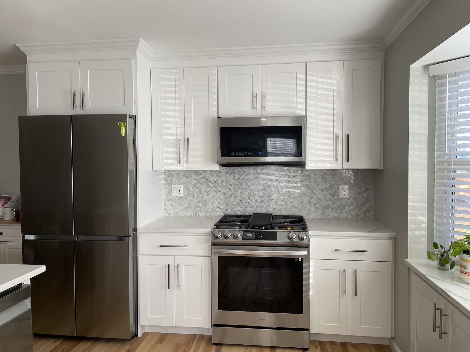 Remodeled kitchen with white shaker cabinets, mosaic backsplash and stainless appliances