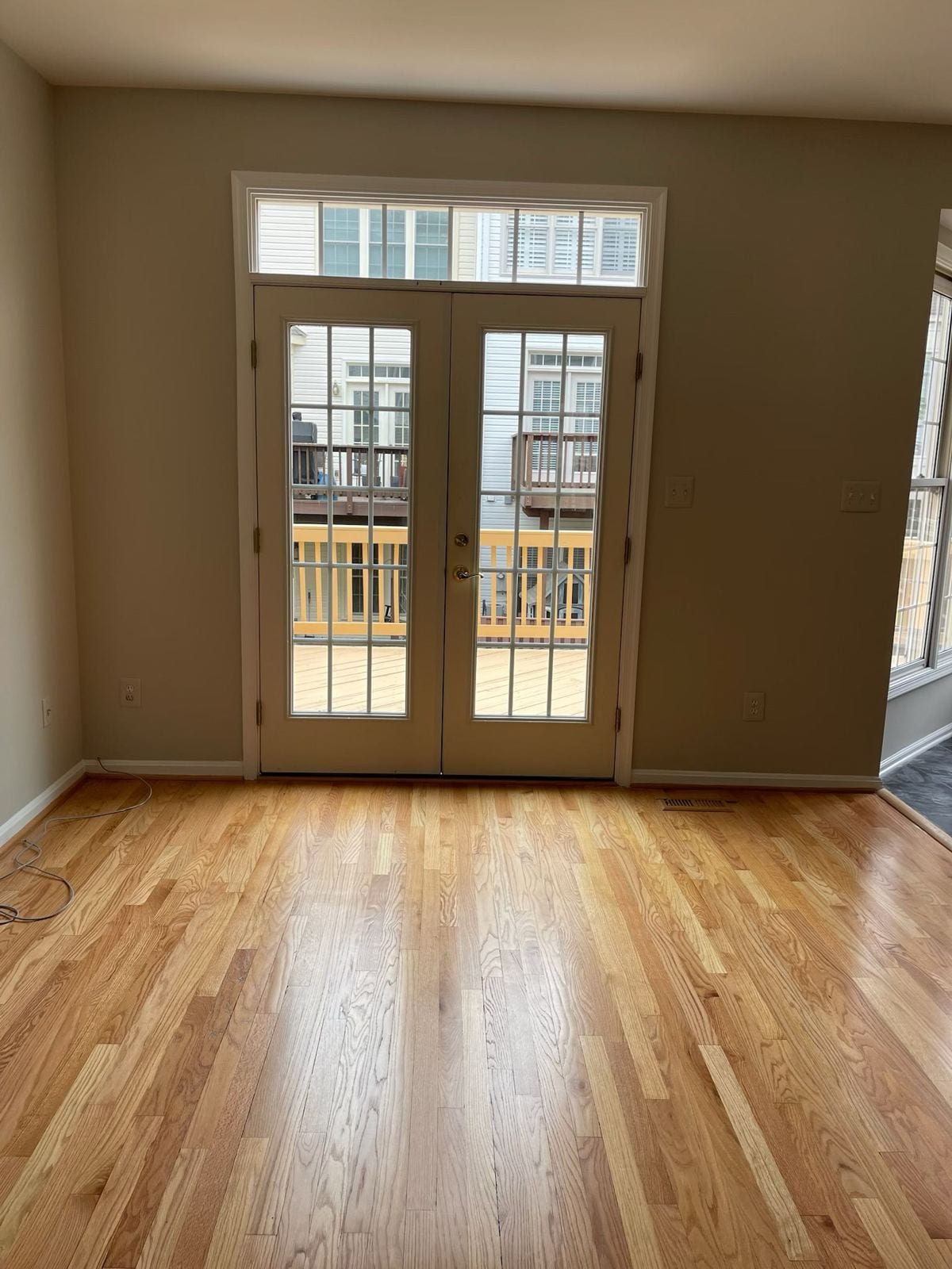 Refinished hardwood floor leading to French doors in a renovated living area