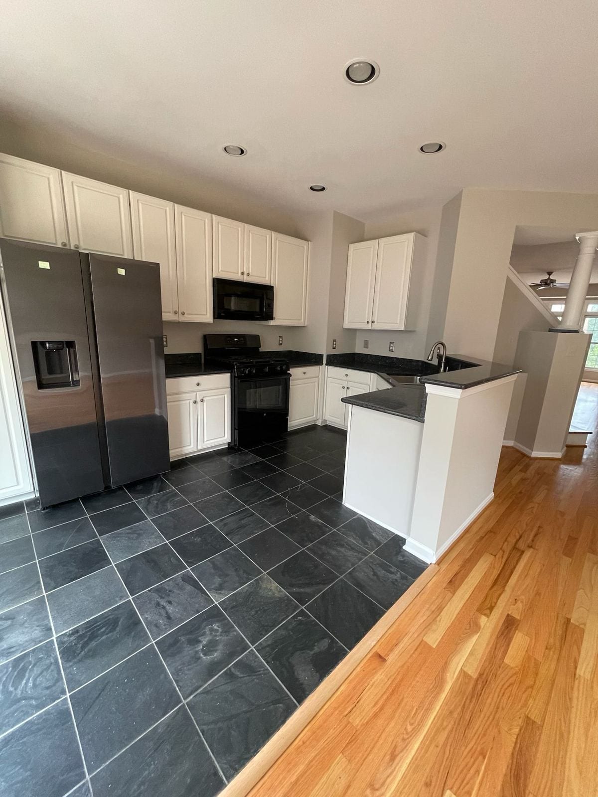 Renovated kitchen with white cabinets, slate tile floor and stainless refrigerator