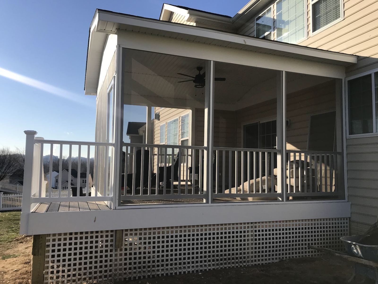 Screened porch with a ceiling fan and white railings, built off the back of the house