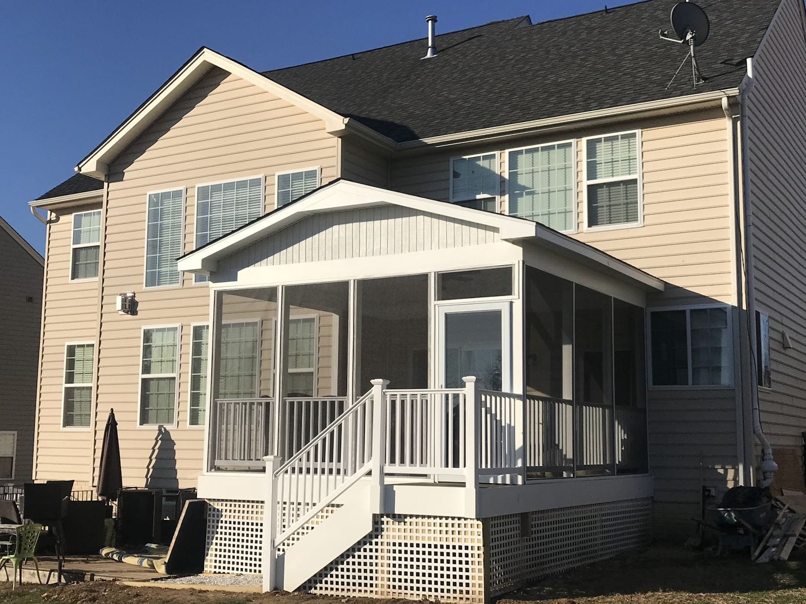 Screened porch addition with a gable roof and white stair on a two-story home
